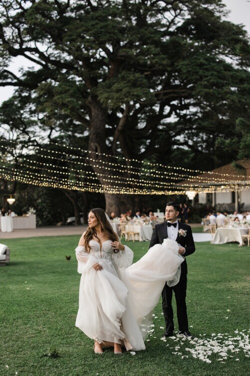 Matias Ezcurra Photography, Bride and groom at Olowalu Plantation House wedding, walking on grass with flower petals.