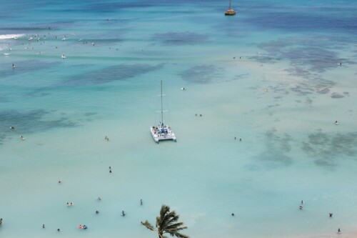 Matias Ezcurra Photography, Aerial view of a catamaran and surfers at Kualoa Ranch, Oahu. Luxury wedding location.