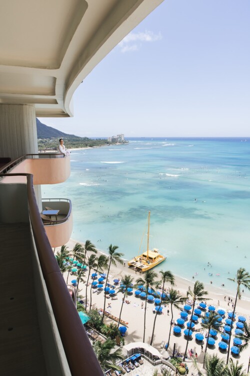 Matias Ezcurra Photography, Ocean view from luxury hotel balcony; woman in white robe on balcony overlooking Waikiki beach.