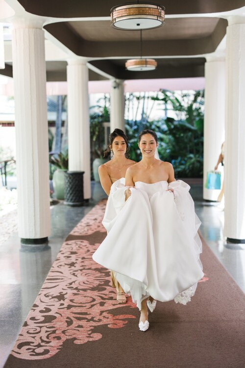 Matias Ezcurra Photography, Bride and bridesmaid walking down hallway at Kualoa Ranch wedding.