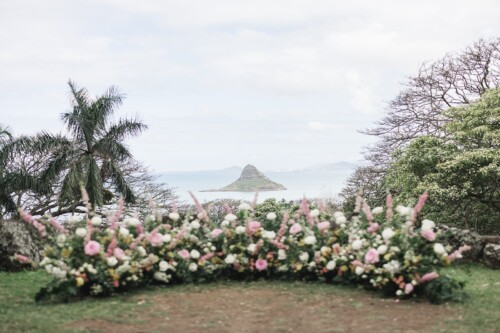 Matias Ezcurra Photography, Floral wedding ceremony setup at Kualoa Ranch, overlooking the ocean and iconic island.