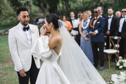 Matias Ezcurra Photography, Bride crying joyfully at her Kualoa Ranch wedding ceremony as her groom looks on.
