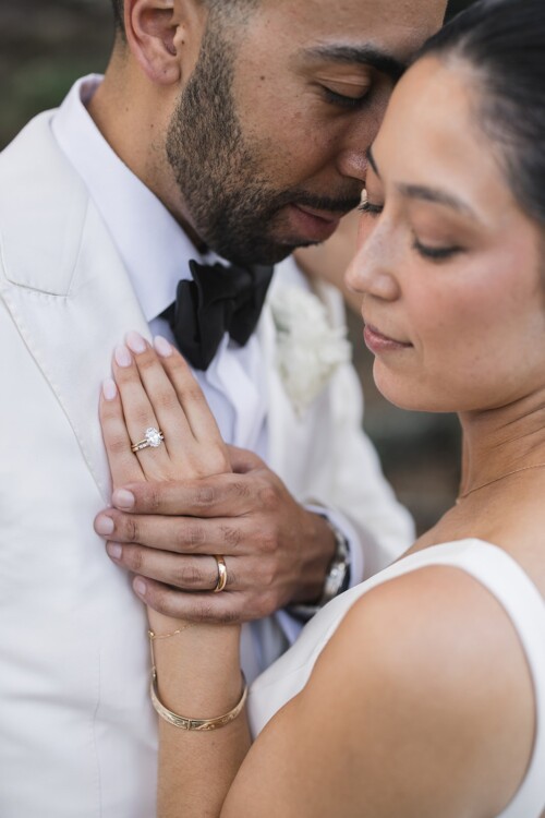 Matias Ezcurra Photography, Close-up of a bride and groom's hands clasped together, showcasing wedding rings. Kualoa Ranch wedding.