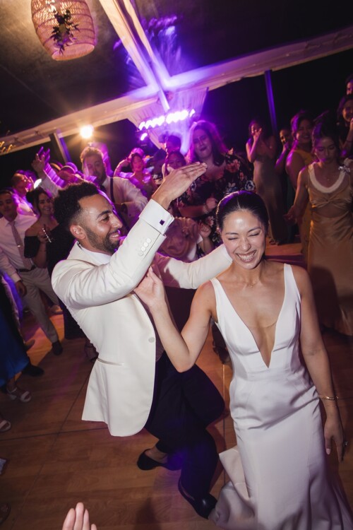 Matias Ezcurra Photography, Bride and groom joyfully dancing at their Kualoa Ranch wedding reception.