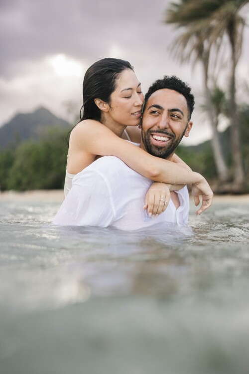 Matias Ezcurra Photography, Happy couple embracing in shallow ocean water at Kualoa Ranch.