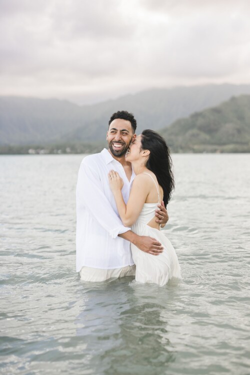 Matias Ezcurra Photography, Happy couple embracing in shallow water at Kualoa Ranch. Klaire and Alex's luxury wedding.