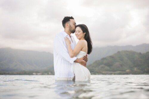 Matias Ezcurra Photography, Klaire & Alex embrace in the ocean at their Kualoa Ranch wedding.
