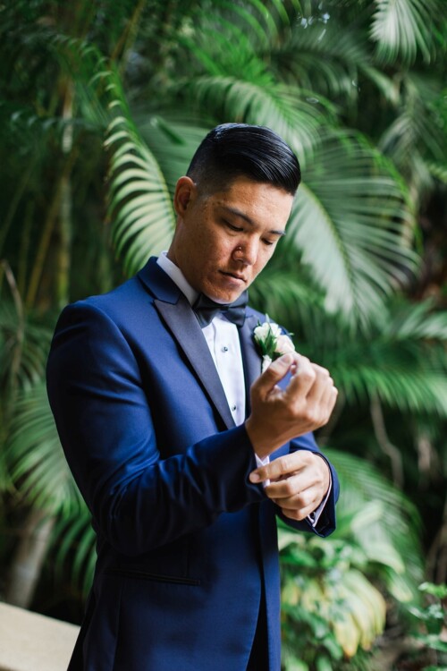 Matias Ezcurra Photography, Groom adjusting cufflinks, wearing a navy tuxedo.