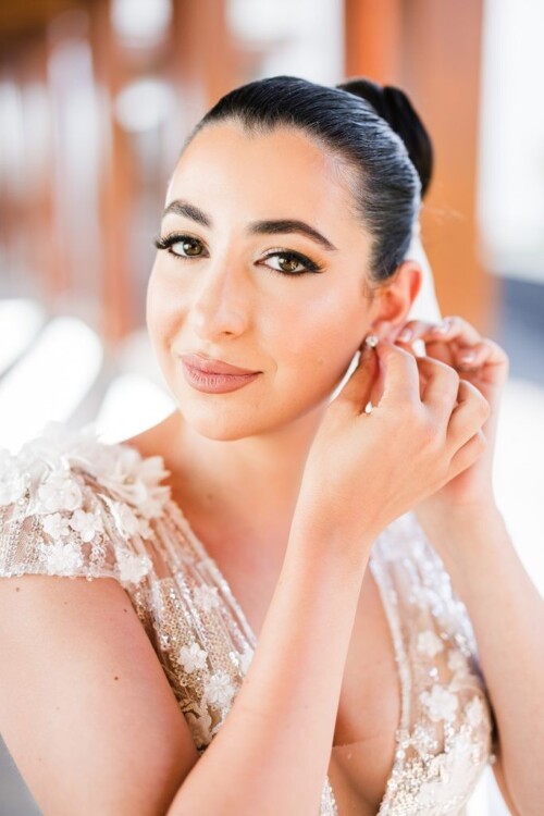 Matias Ezcurra Photography, Bride in beaded wedding dress adjusts earrings. Andaz Maui wedding.