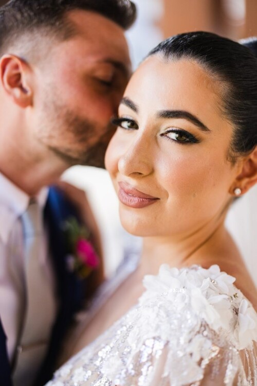 Matias Ezcurra Photography, Bride smiles as groom kisses her cheek at their Andaz Maui wedding.