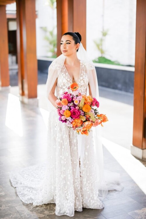 Matias Ezcurra Photography, Bride in embroidered gown holds vibrant floral bouquet at Andaz Maui wedding.