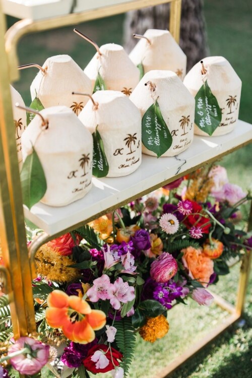 Matias Ezcurra Photography, Personalized coconut drinks and vibrant flowers at an Andaz Maui wedding reception. "Mr. & Mrs. Atimizyan" wedding tags are visible.